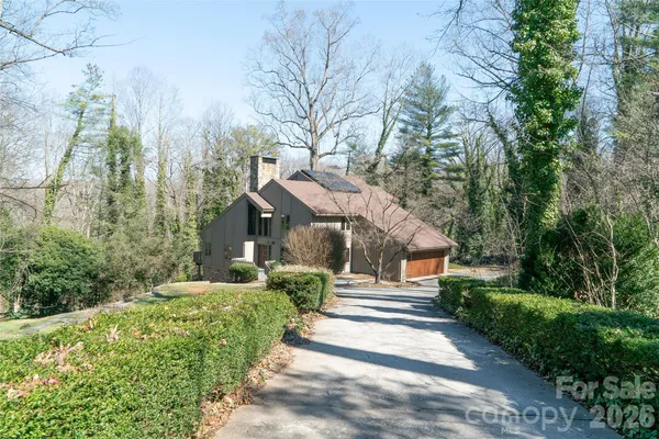 a front view of a house with a yard and large trees