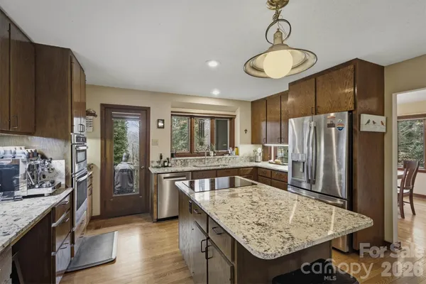 a kitchen with stainless steel appliances granite countertop a sink refrigerator and cabinets