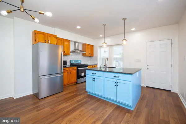 a kitchen with kitchen island wooden floors appliances and cabinets