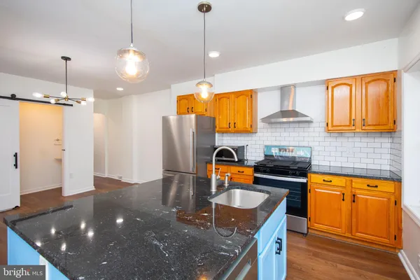 a kitchen with stainless steel appliances granite countertop a sink a stove and a wooden floors