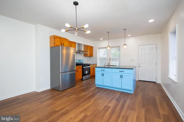 a kitchen with stainless steel appliances granite countertop a refrigerator a sink dishwasher and a stove with wooden floor