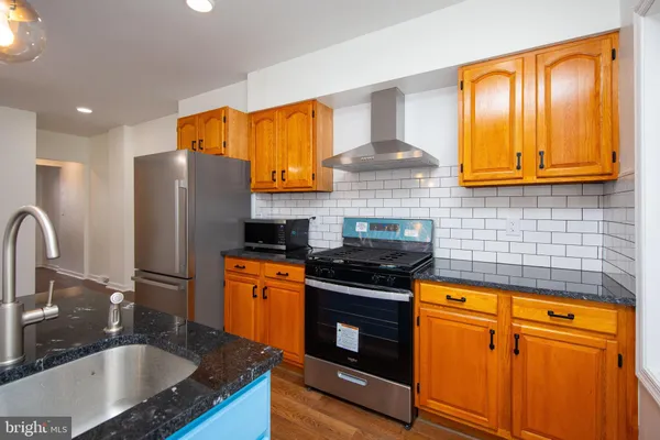 a kitchen with stainless steel appliances granite countertop a sink stove and refrigerator