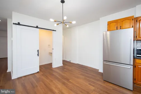 a view of empty room with wooden floor ceiling fan and refrigerator