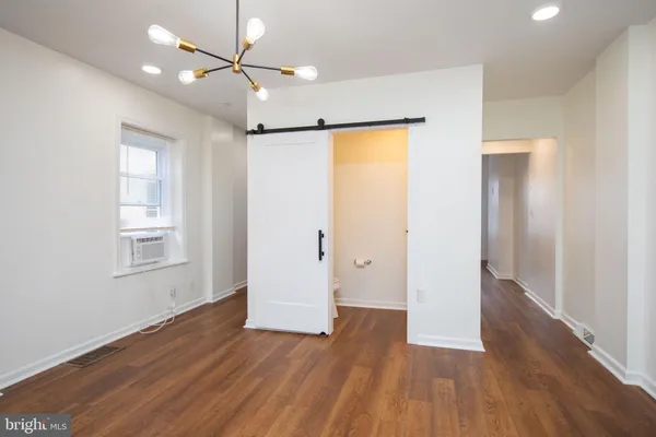 an empty room with wooden floor a ceiling fan and a window