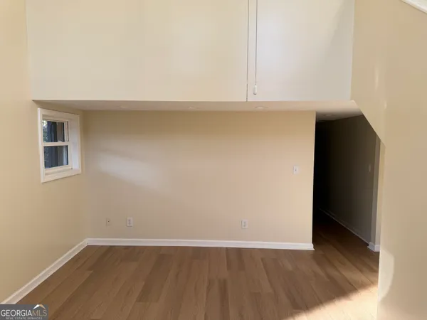an empty room with wooden floor and cabinets