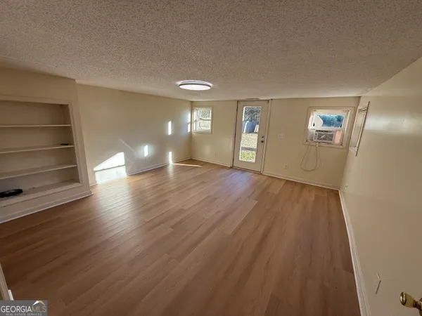 a view of an empty room with wooden floor and a window