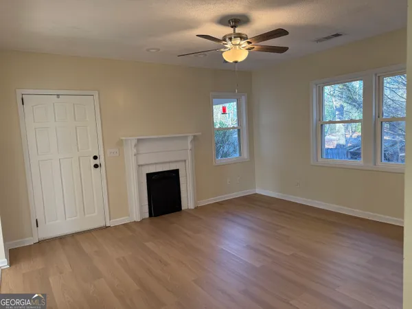 an empty room with wooden floor ceiling fan and window
