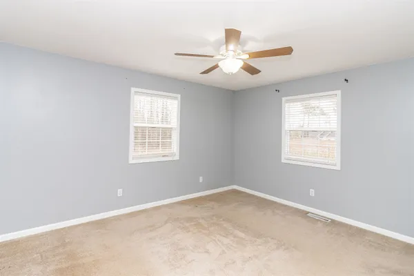 an empty room with windows and fan