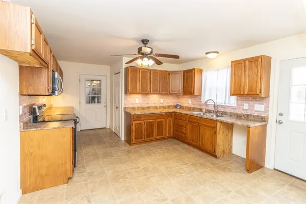 a large kitchen with granite countertop a stove refrigerator and cabinets