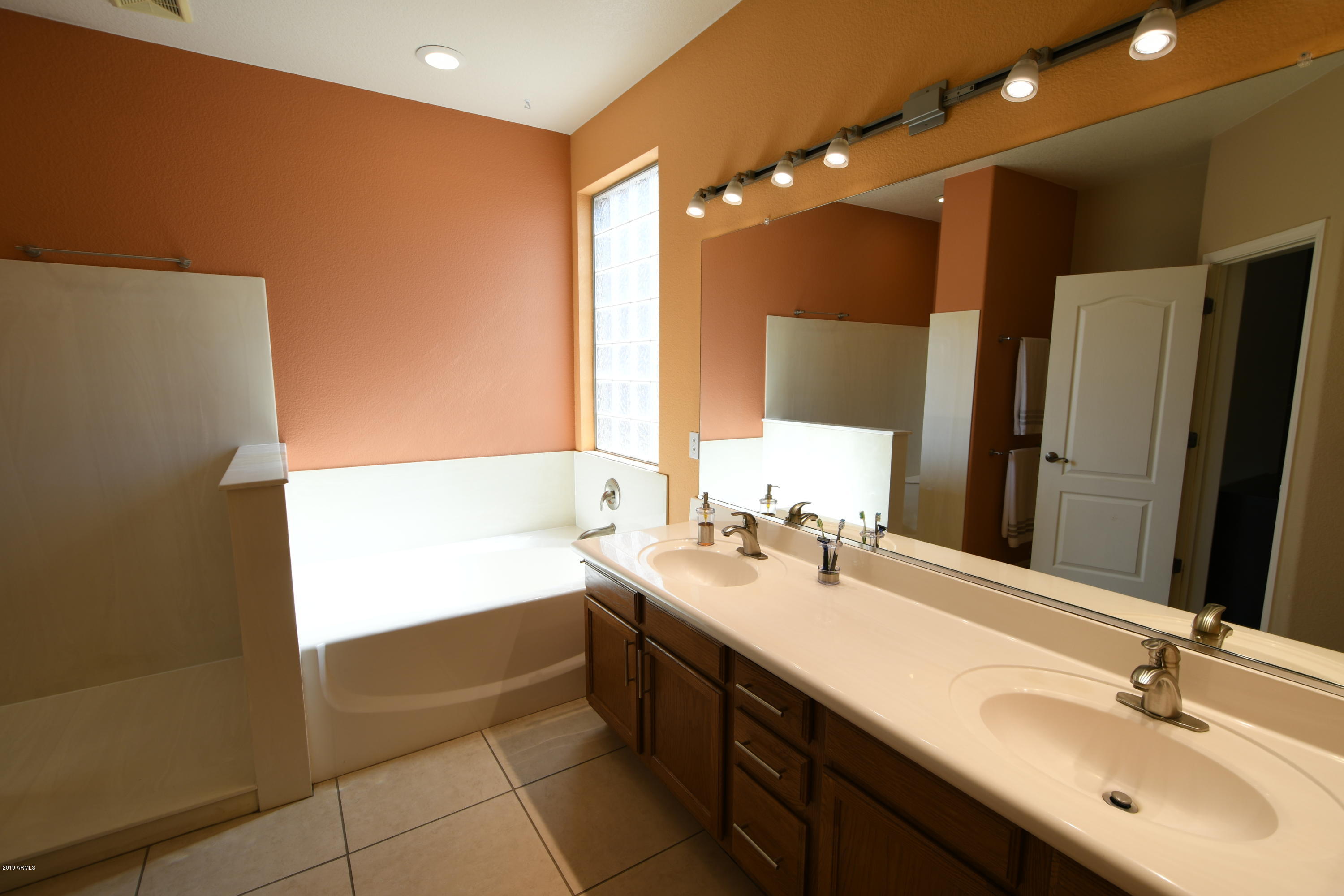 2226 West Carson Road Phoenix, AZ 85041 - Photo 17 of 29 a bathroom with a double vanity sink a mirror and a bathtub
