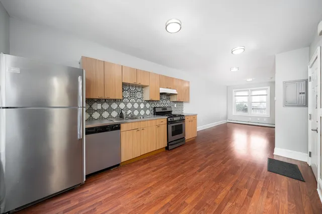 a kitchen with granite countertop a refrigerator and a stove top oven