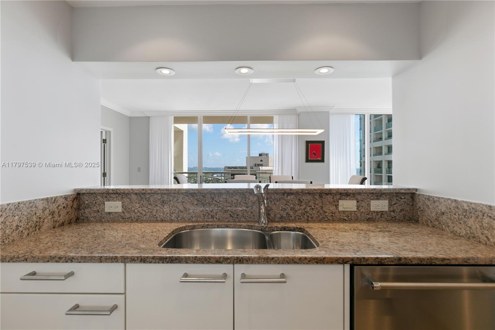 3350 Southwest 27th Avenue, Unit 902 Miami, FL 33133 - Photo 11 of 40 a kitchen with granite countertop a sink and white cabinets
