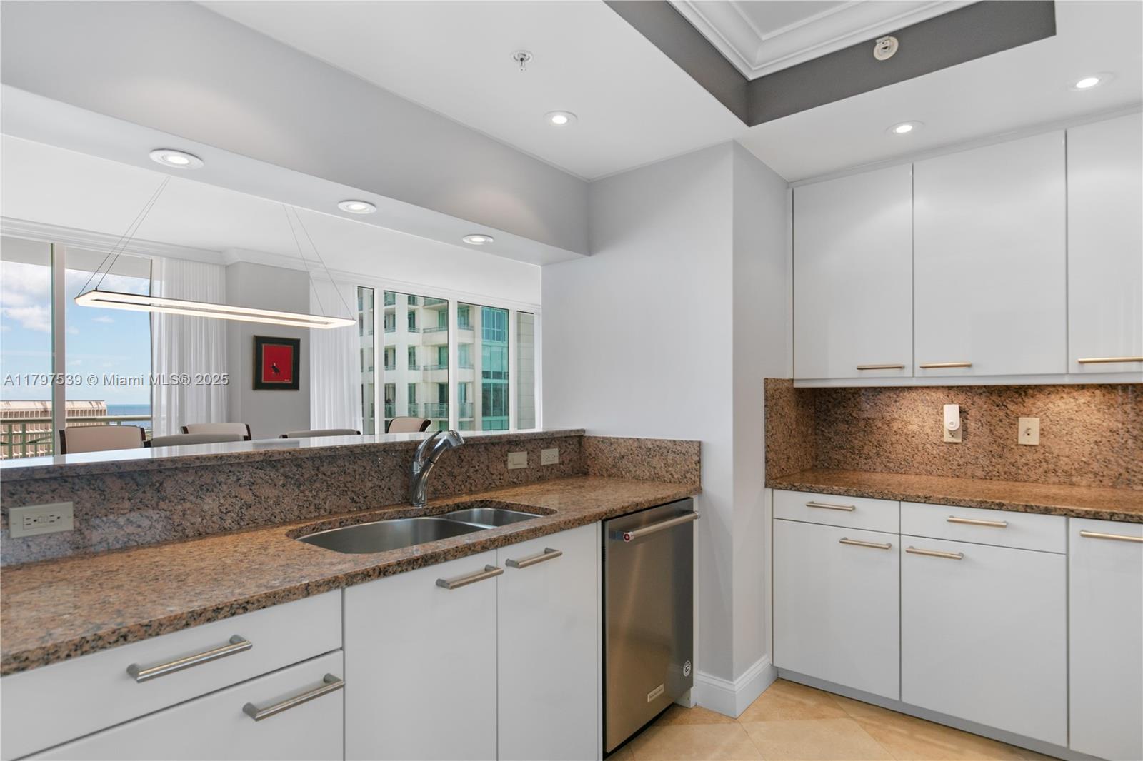 3350 Southwest 27th Avenue, Unit 902 Miami, FL 33133 - Photo 12 of 40 a kitchen with granite countertop a sink and white cabinets