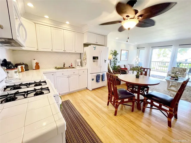 a kitchen with stainless steel appliances a dining table chairs stove and white cabinets