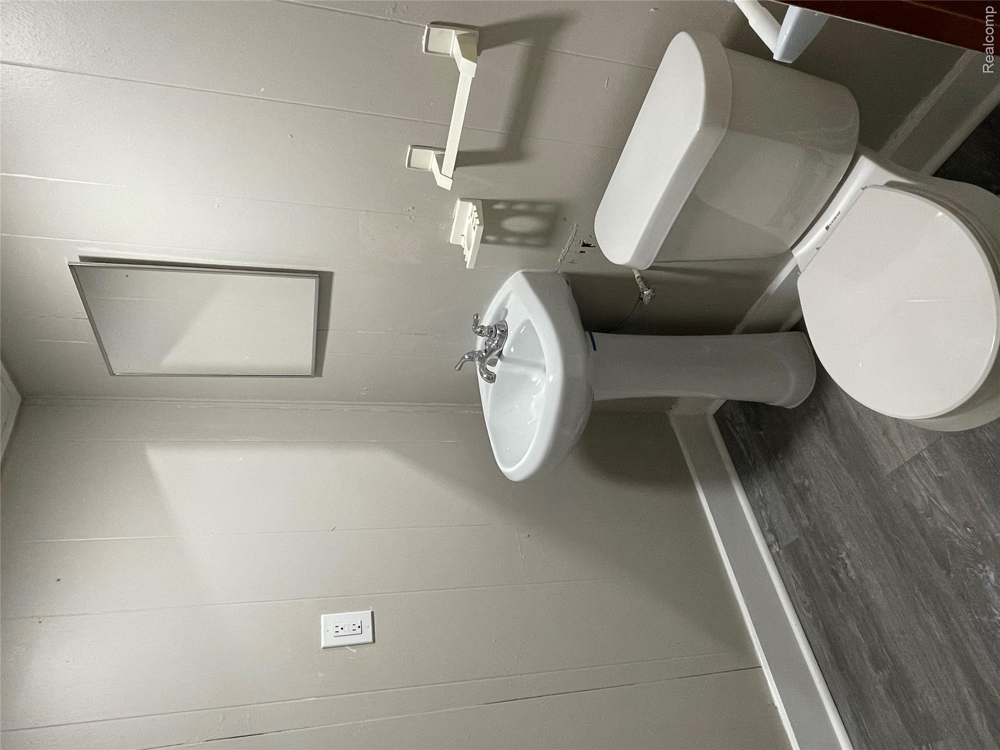 1173 Featherstone Road Pontiac, MI 48342 - Photo 23 of 23 Bathroom featuring a pedestal sink, toilet, and wall-mounted mirror