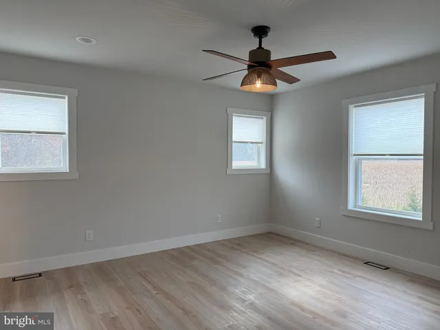 an empty room with windows and fan
