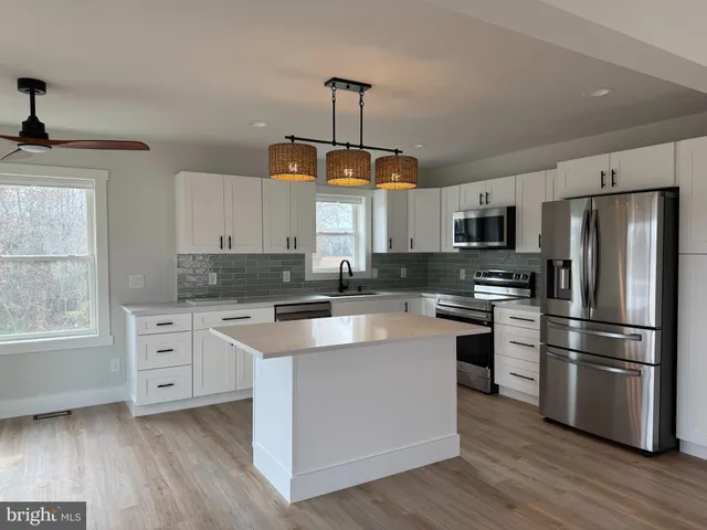 a kitchen with white cabinets stainless steel appliances and window