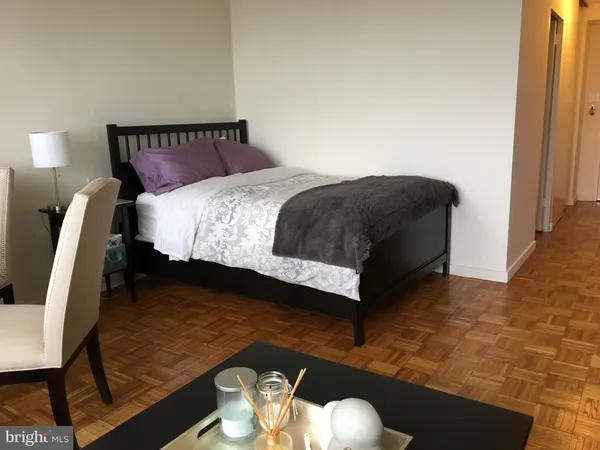 a bed sitting in a bedroom next to a lamp with wooden floor