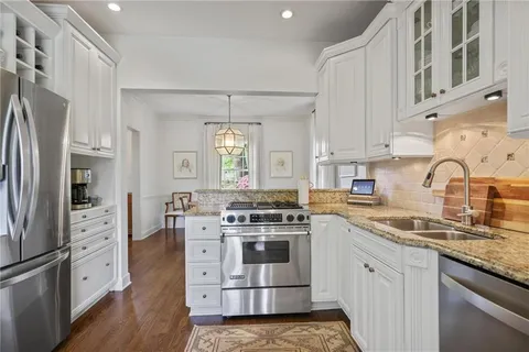 a kitchen with stainless steel appliances granite countertop a stove and white cabinets