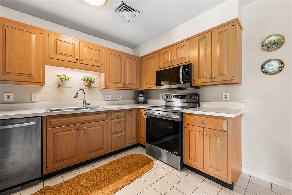 63 Garden Road, Unit C5 Wellesley, MA 02481 - Photo 11 of 30 a kitchen with granite countertop a stove a sink and a microwave