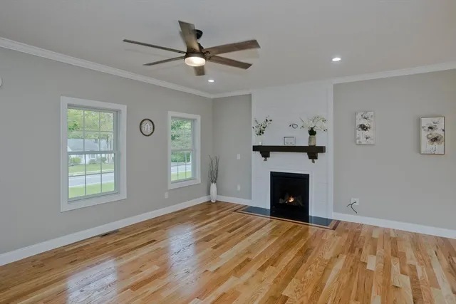 a view of an empty room with wooden floor fireplace and a window