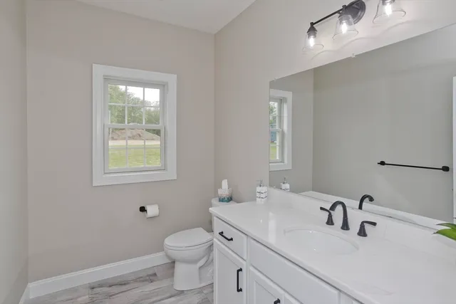 a bathroom with a toilet a sink a mirror and a window