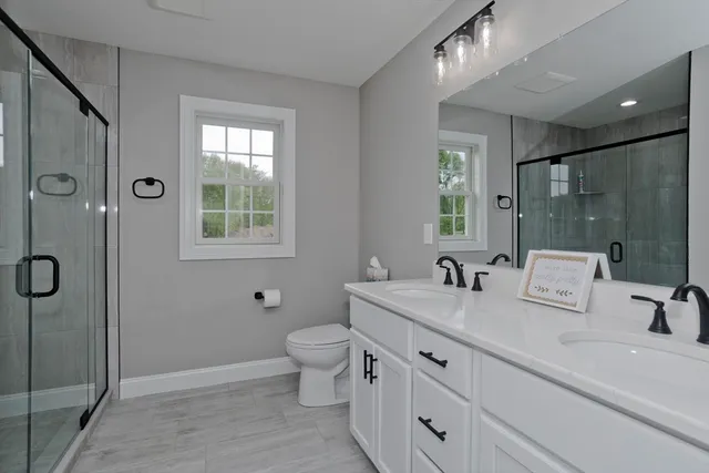 a bathroom with double vanity sink a mirror and a shower