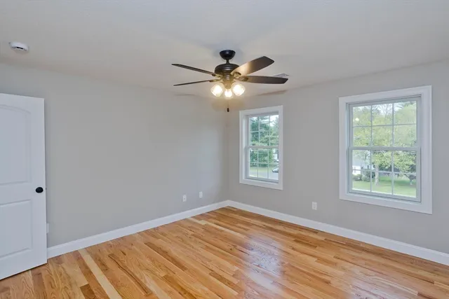 a view of an empty room with window and wooden floor