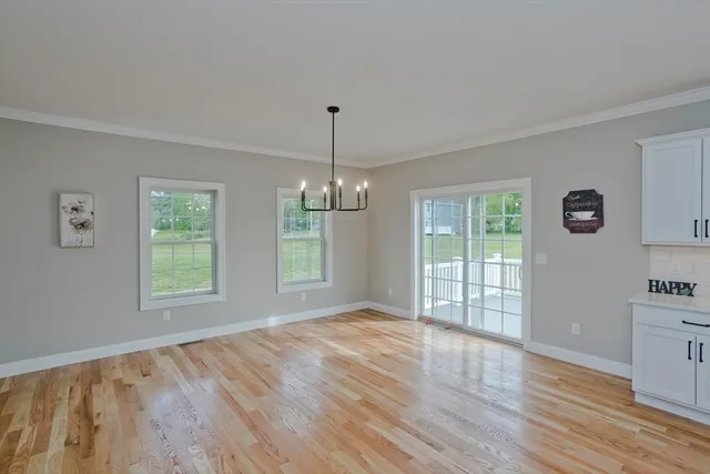 a view of an empty room with window and wooden floor