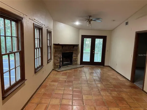an empty room with windows and fireplace