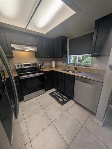 a kitchen with granite countertop a sink stove and cabinets