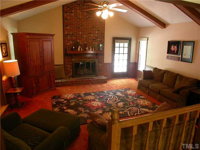 11708 Trottenham Street Raleigh, NC 27614 - Photo 22 of 22 Great room of the home with masonry fireplace, ceiling fan, cath. ceiling, and door to the rear deck. Open floor plan in that railing is part of the breakfast room.