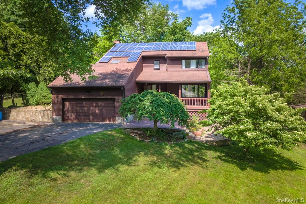 64 Furnace Woods Road Cortlandt Manor, NY 10567 - Photo 33 of 38 View of front of house with a garage, solar panels, and front lawn.