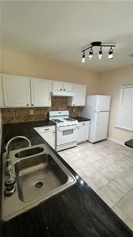 a kitchen with granite countertop a sink stove and cabinets
