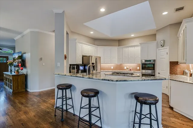 a kitchen with granite countertop a dining table chairs refrigerator and cabinets