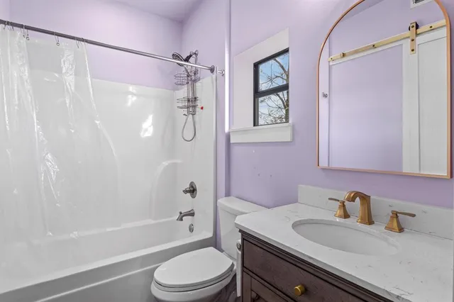 a bathroom with a granite countertop bathtub shower sink vanity mirror and toilet