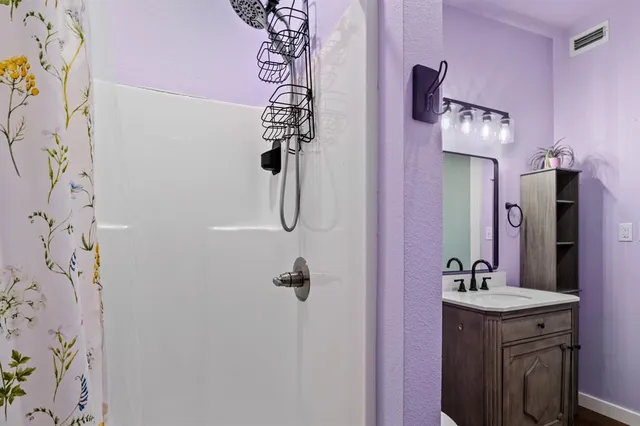 a bathroom with a sink vanity and shower