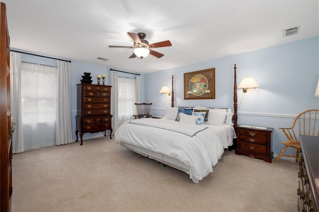 1942 Musket Court Smoke Rise, GA 30087 - Photo 23 of 54 a spacious bedroom with a bed and a chandelier