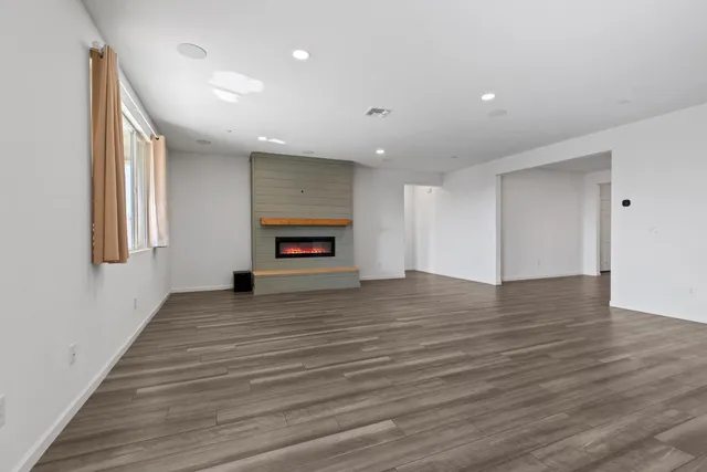 a view of empty room with wooden floor and fireplace