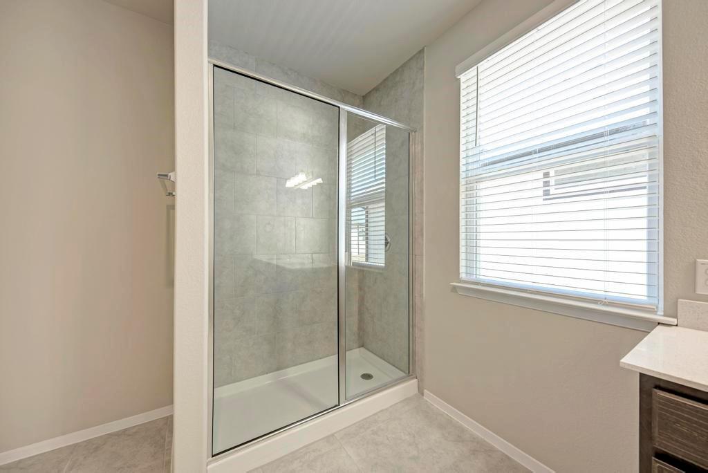 1209 Goforth Road Kyle, TX 78640 - Photo 18 of 32 A well-lit primary bathroom features a spacious glass-enclosed shower with tiled walls.
