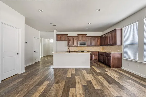 a large kitchen with kitchen island a sink dishwasher a stove and a refrigerator with wooden floor