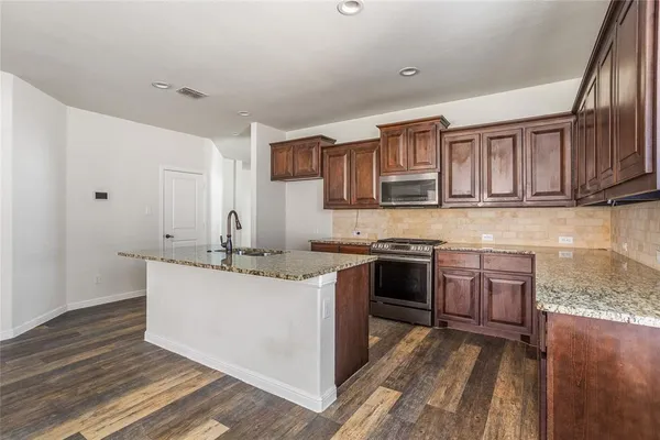 a kitchen with stainless steel appliances granite countertop a sink stove and cabinets