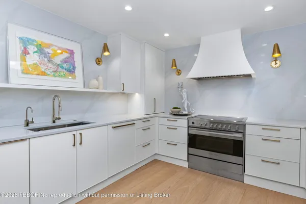 a kitchen with stainless steel appliances a stove a sink and white cabinets