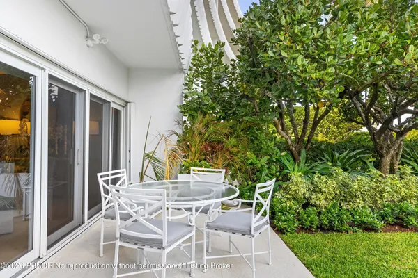 a patio with table and chairs and potted plants