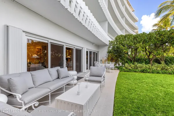 a view of a patio with couches table and chairs with plants and garden
