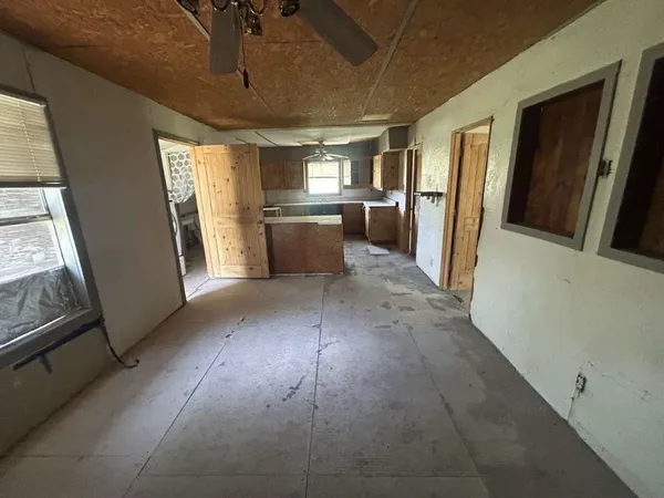 a view of a refrigerator in kitchen and an empty room
