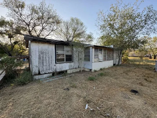 a backyard of a house with large trees and a barn