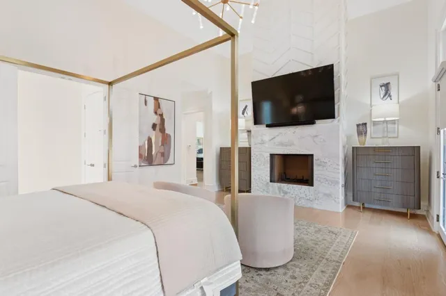 a bedroom with a large bed a flat tv screen and a fireplace
