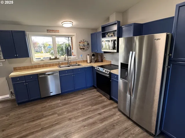 a kitchen with stainless steel appliances granite countertop a refrigerator a sink a stove and a refrigerator