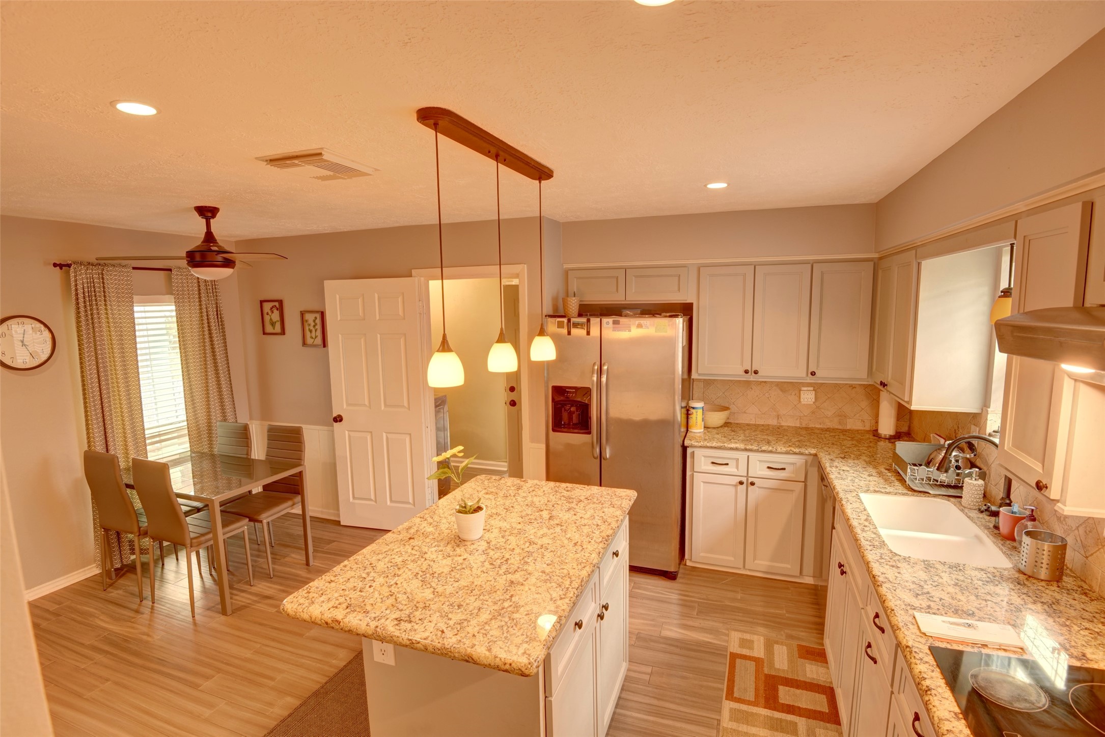 25810 Fairbrook Lane Spring, TX 77373 - Photo 13 of 33 This modern kitchen features a central island with granite countertops, stainless steel appliances, and ample cabinetry. It has recessed lighting, a ceiling fan, and a cozy dining area, creating a comfortable and functional space